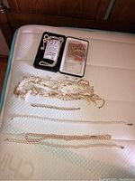 Overall view of six pieces of costume faux pearl jewellery including necklaces and bracelets spread on a mattress.