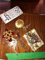 Overview of six brooches and one tray of cufflinks on wood surface