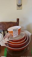 Stacked Pyrex nesting mixing bowls in orange and white colors, with price tag visible on top bowl