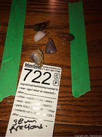 Five semi-precious stone pendants arranged on a wooden surface with green tape on sides and auction tag.