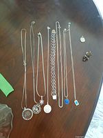 Overhead view of seven necklaces, bracelet, and pair of maple shade earrings arranged on table
