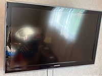 Front view of Samsung 40-inch TV with black bezel and screen reflecting light and room.