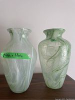 Two translucent glass vases with green and white swirl patterns on wooden surface. One marked 'Made in Italy' and approx. 12 inches tall.