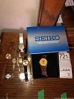 All watches arranged on wooden surface including Seiko watch and box with manual
