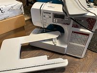 Full view of Brother HC3010 sewing machine with removable extension table attached, showing front digital panel and floral side design.