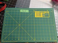 Green Olfa rotary mat cutting board, labeled and with yellow measurement grid in inches, photo showing surface and scale.
