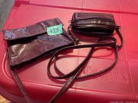Red leather shoulder bag and matching wallet laid out on a pink surface.
