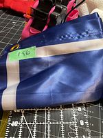 Close-up of the corner of the folded blue nylon flag showing grommet and a price tag labeled '150'.