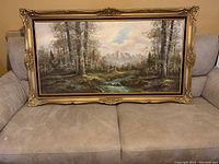 Full view of the oil painting showing a forest landscape with a river and gold decorative frame.