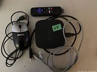 Full view of Roku TV box, remote control, Dell wired mouse, and various cables on a table