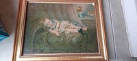 Framed antique Victorian print titled 'Sleeping Child' showing a young child sleeping on a green patterned couch seen from above.