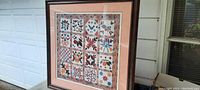Framed quilt picture print shown angled to highlight frame and matting with glass reflection