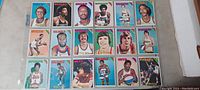 Photo of one sheet with 20 early 1970s NBA basketball cards in plastic sleeve showing player images and team logos.