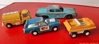 Top view of four vintage toy vehicles on red background showing all from side angle