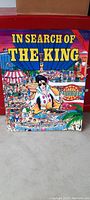 Front cover of the booklet titled 'In Search of The King' featuring colorful cartoon-style illustrations and an Elvis Presley figure.