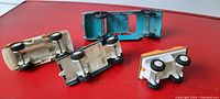 Four vintage metal toy vehicles seen from the bottom, showing their metal base and wheels.