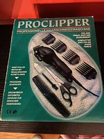 Photo of the Proclipper branded box showing the full hair cutting kit including clipper, scissors, comb attachments, and screwdriver.
