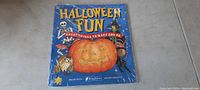 Full front cover of the sealed Halloween fun activity book for kids showing colorful Halloween illustrations and text.