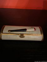 Top view of vintage white Art Deco cigarette case with a pipe design on top and gold clasp