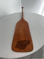 Full length image of cherry wood paddle highlighting its shape and wood grain.