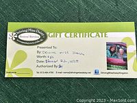 Photo of the $50 Driving Miss Daisy Kingston gift certificate on a green textured surface showing the certificate details and branding.