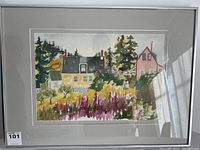 Front view of framed watercolour painting showing village scene with houses, trees and flowers.