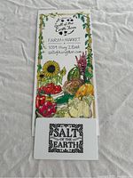 Photo of the Salt of the Earth Farm $50 gift certificate card placed over a colorful pamphlet depicting farm produce and contact info.
