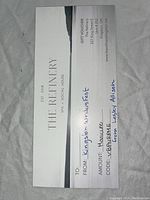 Photo of a white gift voucher labeled 'The Refinery', indicating a $50 value manicure at 327 King St East, Kingston.