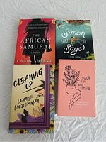 Top view of four young adult fiction books arranged flat: The African Samurai, Simon Sort of Says, Cleaning Up, and Suck It In and Smile.
