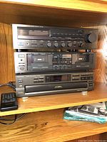 Yamaha RX-330 receiver on top, Yamaha KX-W302U cassette player in the middle, Technics SL-PD847 CD changer at bottom on wooden shelf. Also remote control visible.