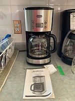 Photo of Sunbeam coffee maker on countertop with user manual and other instructions next to it.