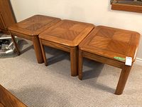 Photo of three wood end tables side by side with geometric patterned tops and rounded legs.
