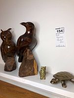 Four figurines displayed on a white shelf: Two wood carved birds (one owl), one brass-look owl, and one brass-look turtle trinket box. Photo shows relative size and condition of items.