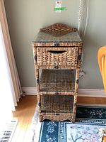 Front view of the wicker and wood phone table showing the drawer, two shelves, and the glass top.