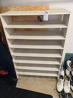 Front view showing eight shelves and white painted surface with scratches.