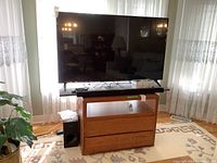 LG 55" TV on wooden stand with Samsung soundbar in front and subwoofer to left