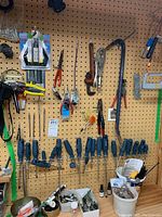 Pegboard with screwdrivers, pliers, hand saws, and other hand tools calling out various types and sizes hung neatly for display.