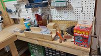Workbench with various tools and hardware items including the power adapter box, wood pieces, metal drill bits, and miscellaneous hardware parts.