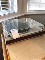 Front view of turntable with closed acrylic dust cover and wood plinth