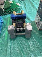 Overview of several dumbbells including a large grey 20 lb metal dumbbell and beige dumbbells, black leg weight.