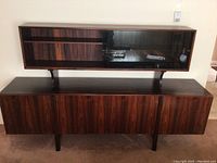 Front view of assembled two-tier cabinet showing wood veneer pattern and sliding glass doors