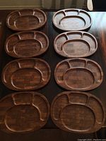 Eight oval wooden serving trays arranged in two columns, showing their divided compartments and wood block pattern.