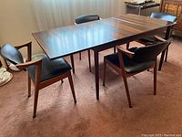 Set of table and chairs in room with carpet and curtain backdrop