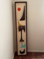 Full front view of framed wood relief art leaning against wall