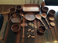 Wide view of the wooden serving bowls, plates, utensils, and accessories arranged on a table.