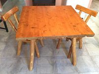 Square wooden table with two wooden chairs, showing natural finish and wood grain.