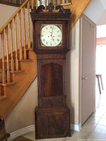 Full view of entire wooden longcase clock showing overall height, case style, and pediment.