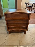 Full front view of wood cabinet showing three curved drawers and surface wear.