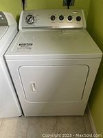 Front view of white Whirlpool dryer with closed door and control panel
