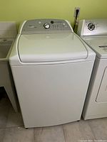Full front view of white top-load washer beside dryer